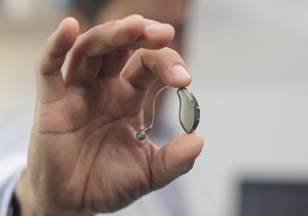 Closeup of hand holding a hearing aid.