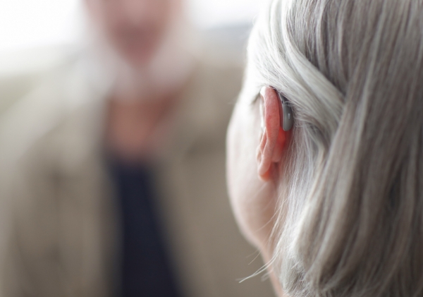 Closeup of a hearing aid behind an hear on a patient.