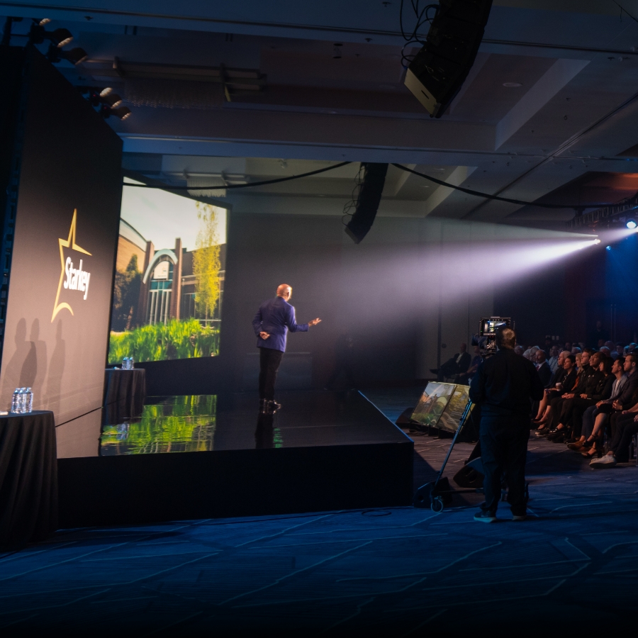 Brandon speaking on stage to a stadium of people.